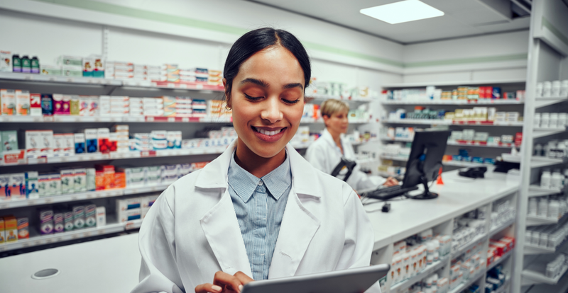 smiling pharmacist looking at tablet