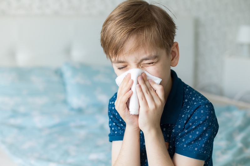 boy with seasonal allergies blowing his nose
