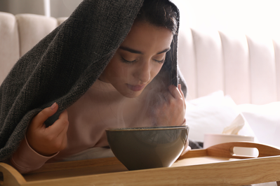 young woman inhaling steam from bowl
