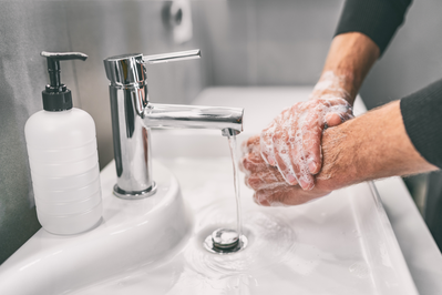 man washing hands and arms with soap and water