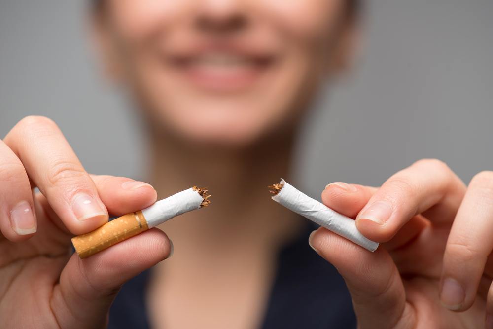 woman's hands breaking cigarette in half