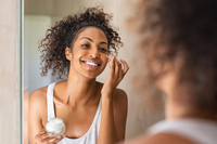 young woman applying moisturizer to face