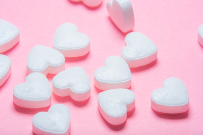 white heart-shaped pills on pink background