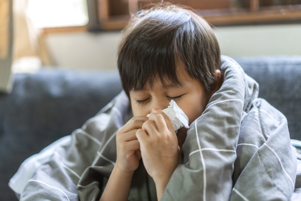 young boy with RSV blowing nose in tissue