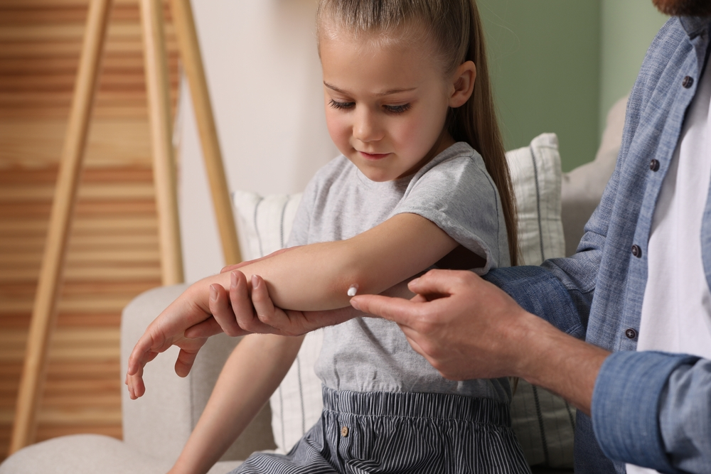 father applying ointment to daughter's elbow